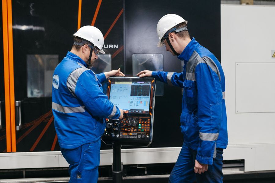 Dois profissionais operando o painel de uma máquina industrial